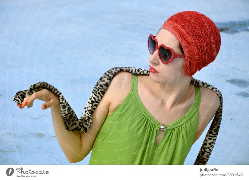 Das Mädchen mit der schönen roten Badekappe und grünem Badeanzug sitzt elegant im leeren Nichtschwimmerbecken. Eine Sommerliebe. Frau Badebekleidung Badehaube