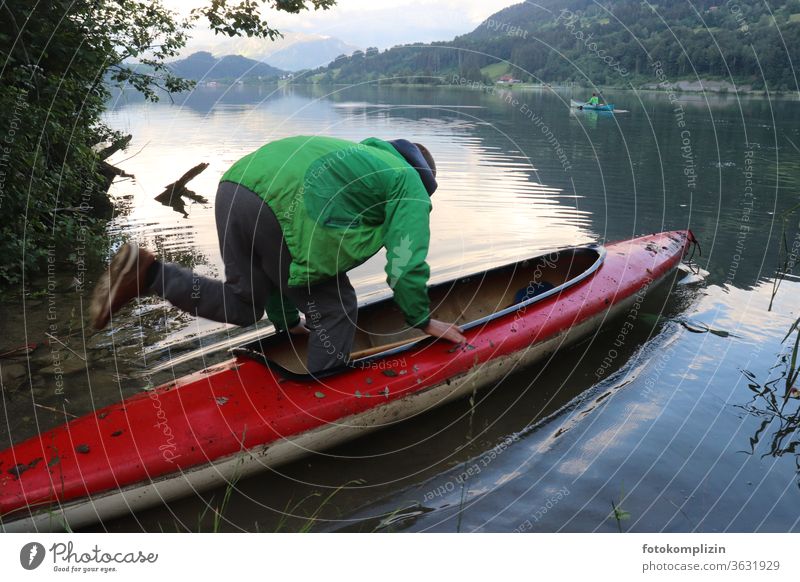 Mensch springt in ein Paddelboot an einem See Bootsfahrt bootfahren bootstour Bootcamp Seeufer Wasserfahrzeug Ruderboot Ferien & Urlaub & Reisen Ausflug