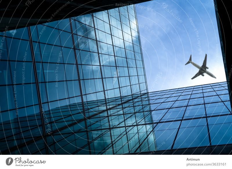 Flugzeug fliegt über einem modernen gläsernen Bürogebäude. Perspektivische Ansicht eines futuristischen Glasgebäudes. Außenansicht des gläsernen Bürogebäudes. Geschäftsreise. Spiegelung in transparentem Glas. Fenster eines Unternehmens.