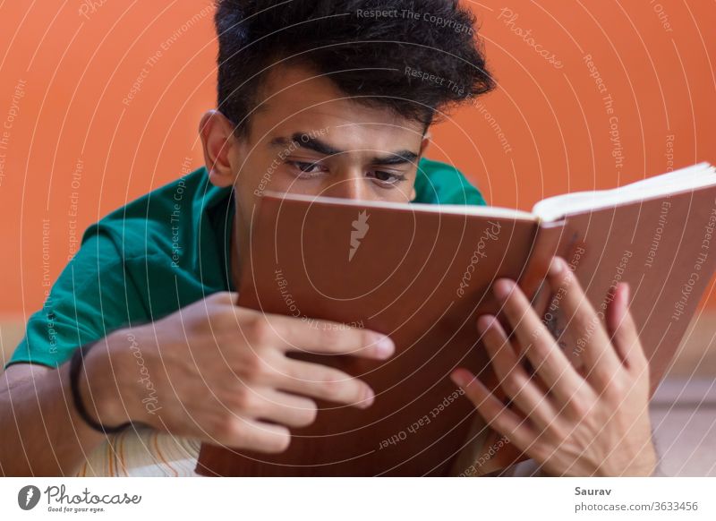 Junger Mann liest ein Buch, während er auf seinem Bett liegt. Aufenthalt in jung lesen Hobby Isolation männlich tausendjährig Sitzen schnorren Coronavirus