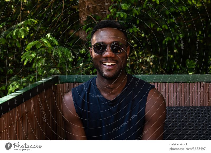 Junger schwarzer Mann lächelt vor der Kamera im Freien 1 Mensch afrikanische ethnische Zugehörigkeit Sonnenbrille Lifestyle in die Kamera schauen Terrasse