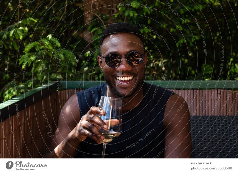Schöner schwarzer Mann mit einer Tasse Wein in der Hand lächelt weit draussen 1 Mensch afrikanische ethnische Zugehörigkeit Sonnenbrille Weißwein Beteiligung