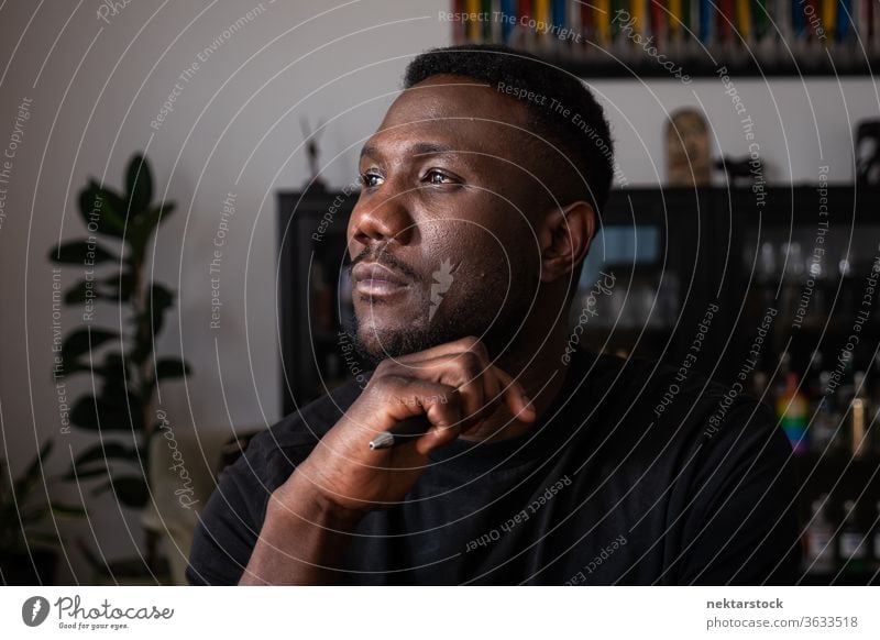 Porträt eines Schwarzen, der im Wohnzimmer denkt Mann 1 Mensch Hand am Kinn afrikanische ethnische Zugehörigkeit Lifestyle 20-30 Jahre alt gutaussehend