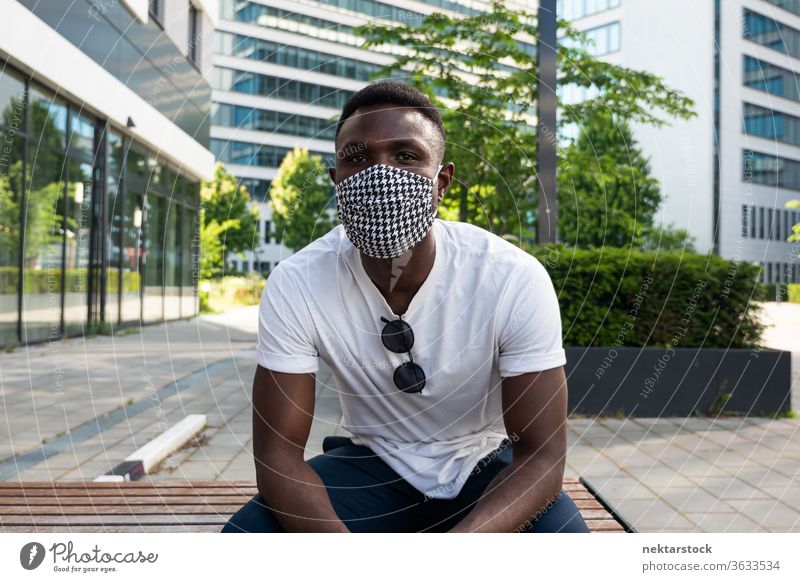 Junger schwarzer Mann mit Gesichtsmaske, der in die Kamera schaut Mundschutz 1 Mensch afrikanische ethnische Zugehörigkeit Lifestyle in die Kamera schauen Bank