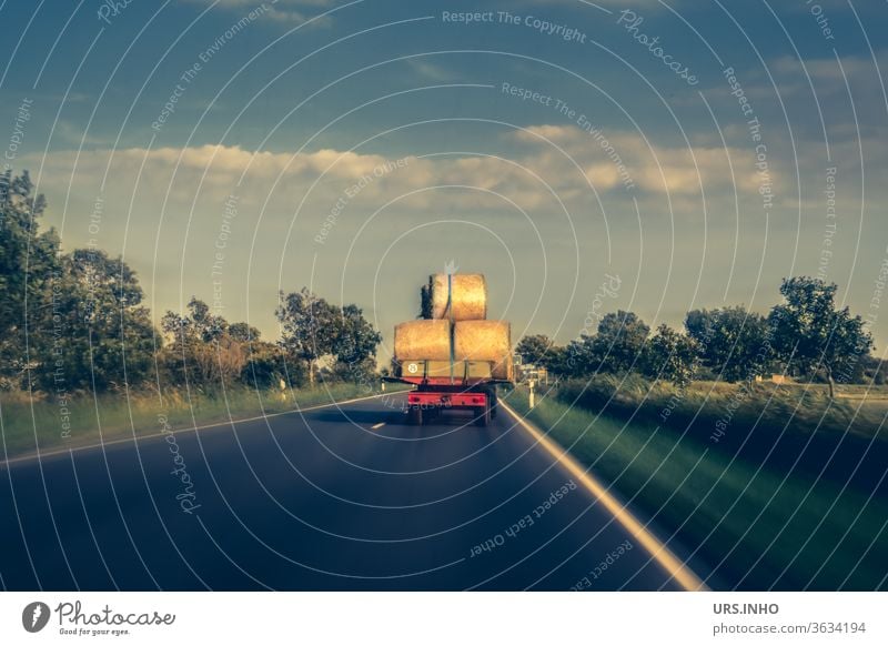 ein Traktor fährt mit Heuballen beladen auf einer Landstraße Landwirtschaft Ernte Natur wolkig Sommer Ackerbau Farbfoto Feld Felder fahren ernten Fahrzeug