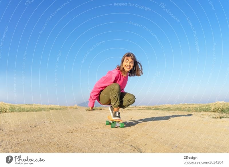 Junge Frau mit rosa Trikot, die auf einem Fußweg Skateboard fährt urban 1 Spaß jung Mädchen Mode Latein hispanisch Textfreiraum Lächeln 20s Holzplatte