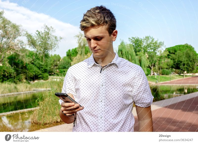 Junger blonder Mann benutzt ein Mobiltelefon im Freien männlich 1 Telefon Mobile jung Person Teenager Smartphone Typ Menschen Straße Mode Großstadt Lifestyle