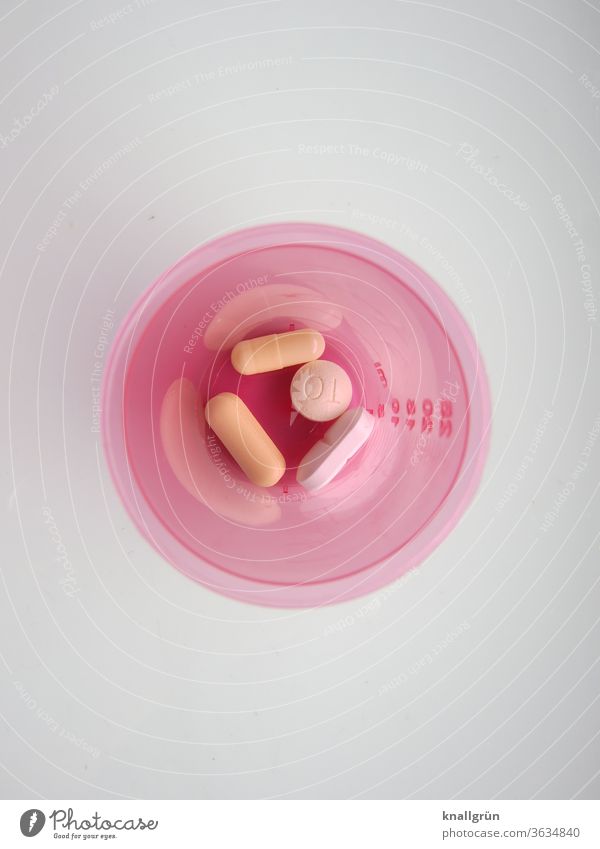 Rosa Plastikbehälter mit vier unterschiedlichen Tabletten aus der Vogelperspektive Gesundheit Medikament Pharmazie Sucht Rauschmittel Gesundheitswesen