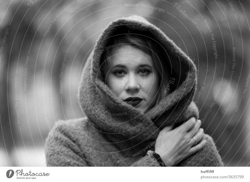 Die junge Frau im Mantel mit Kapuze schaut in die Kamera Porträt Junge Frau Frauengesicht unscharfer Hintergrund 18-30 Jahre Erwachsene portraite Mensch feminin