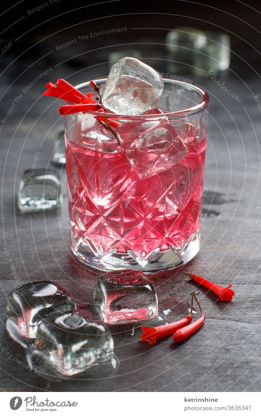 Kosmopolitischer Cocktail in einem mit rosa Blumen dekorierten Glas Kirsche weltoffen Barkeeper Eis grau Werkzeuge Stahl Alkohol Sommer erfrischend Party