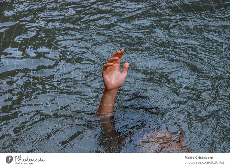 Eine Hand, die aus dem Wasser ragt, um das Konzept des Ertrinkens, der Krise der psychischen Gesundheit, der Depression und des Kampfes zu zeigen