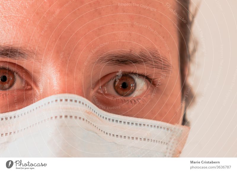 Nahaufnahme eines überarbeiteten Krankenpflegers mit einer chirurgischen Maske Kaukasisch männlich Augen weit geöffnet Operationsmaske covid-19-Pandemie