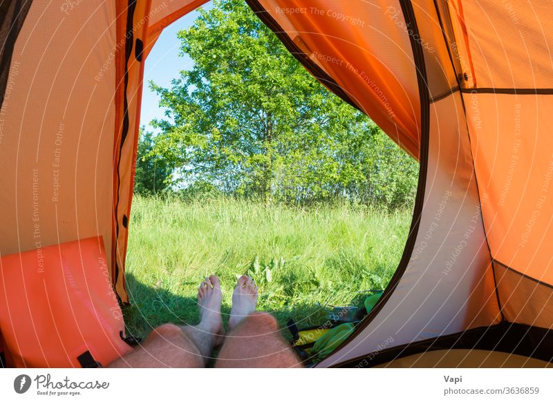 Mann ruht sich im orangefarbenen Zelt aus Lager Urlaub Camping Beine Natur im Inneren Ansicht Gras Fuß Menschen ruhen Erholung Wald Baum Landschaft Abenteuer