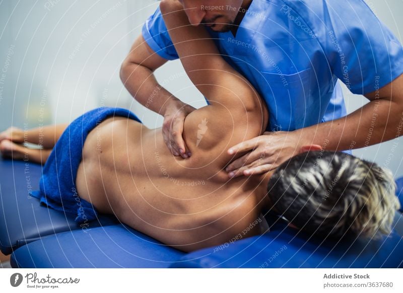 Orthopäde hebt den Arm eines Sportlers während einer medizinischen Untersuchung geduldig Wiederherstellung untersuchen Rücken professionell Arme Osteopathie