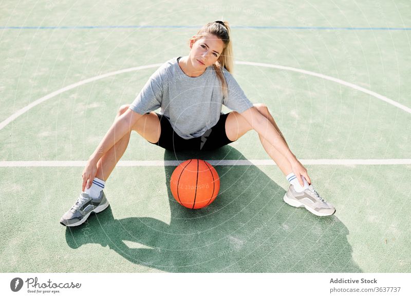 Basketballspielerin auf dem Sportplatz sitzend Frau Übung Aufwärmen Sportpark Training vorbereiten Spieler Ball Gericht Aktivität Lifestyle Wohlbefinden jung
