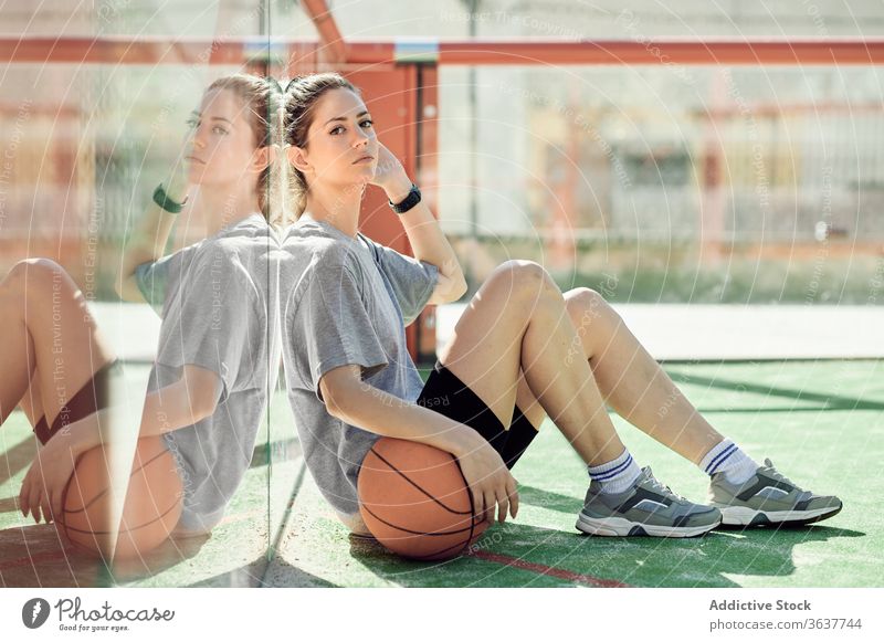 Müde Sportlerin mit auf dem Platz liegendem Basketball Frau sich[Akk] entspannen ruhen müde Gericht sitzen Ball jung Athlet Sportbekleidung Training Aktivität