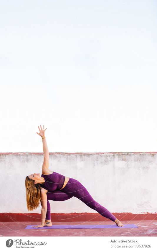 Konzentrierte Frau macht Yoga in erweiterter Seitenwinkelstellung beweglich üben Unterlage utthita parsvakonasana erweiterte Seitenwinkelstellung Wellness Asana