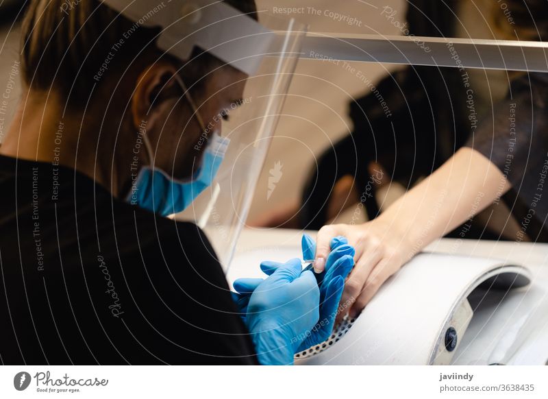 Ästhetiker, der die Maniküre macht, feilt die Nägel mit einer Feile seiner Kundin in einem Schönheitszentrum Aktenordner nageln Nagellack Fingernagel Frau Salon