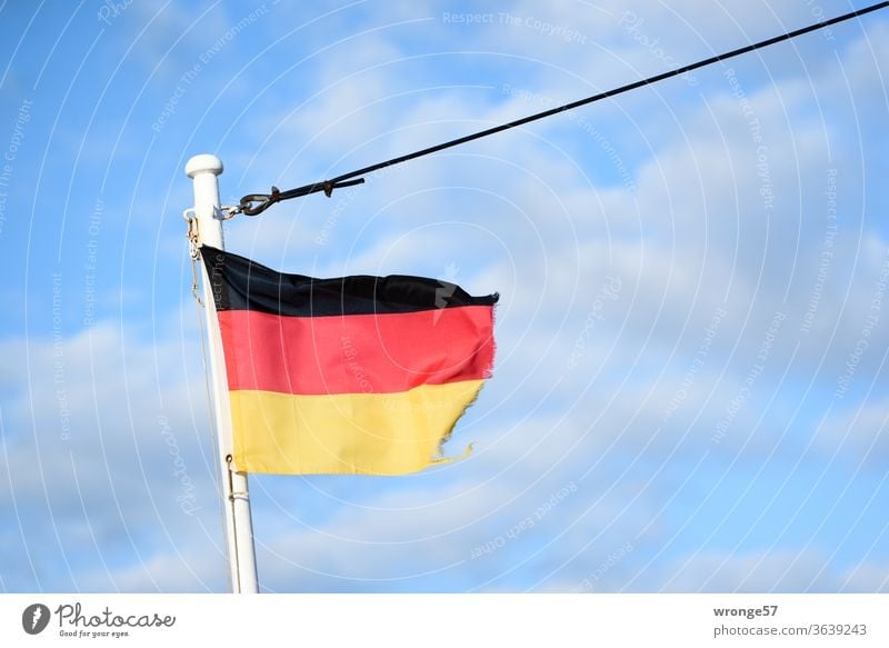 Ausgefranste deutsche Flagge flattert im Wind am Mast eines Schiffes unter blauem Himmel Fahne Deutschland Deutsche Flagge Bugmast Fahnenmast schwarzrotgold