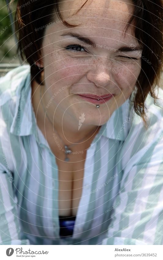 Portrait einer jungen, sommersprossigen Frau zwinkert und lächelt junge Frau Top windig Haare brünett schön intensiv Jugendliche 18-25 Jahre Dekolleté