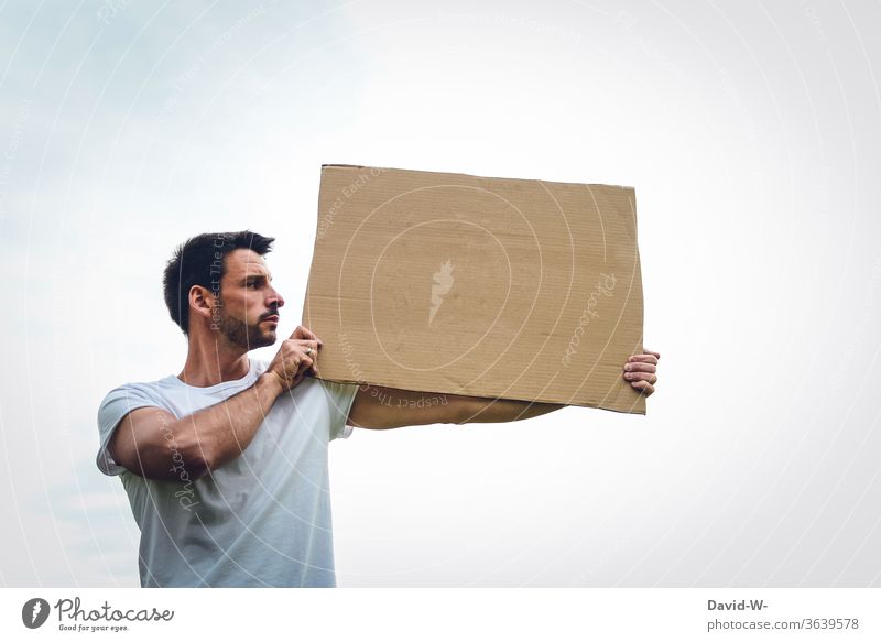 eine Person hält ein Pappschild aus Karton in den Händen, präsentiert es und schaut sich an was dort geschrieben sein könnte Meinungsäußerung Meinungsfreiheit