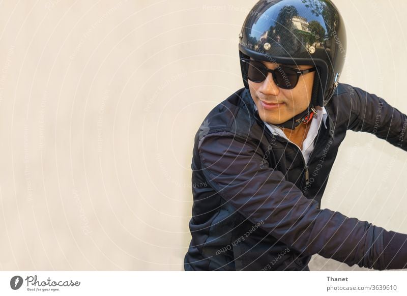 Junger asiatischer Motorradfahrer in schwarzer Jacke blickt beim Motorradfahren zurück. Biker schwarze Jacke gutaussehend Schutzhelm Mann Reiter Sonnenbrille