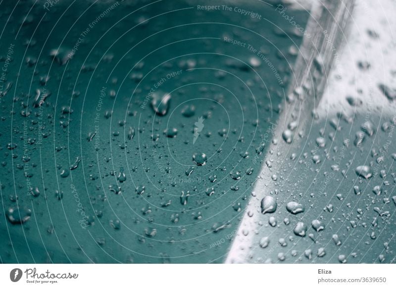 Wassertropfen nach dem Regen auf der Motorhaube eines Autos nass Lack blau Tropfen abperlen Detailaufnahme Metall Wetter Reflexion & Spiegelung PKW