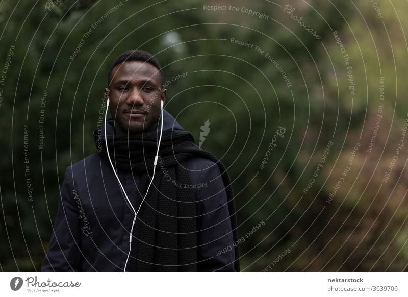 Junger Mann hört Hörbuch im Park Porträt Kopfhörer afrikanische ethnische Zugehörigkeit schwarz öffentlicher Park hören Musik Modell aus dem wirklichen Leben