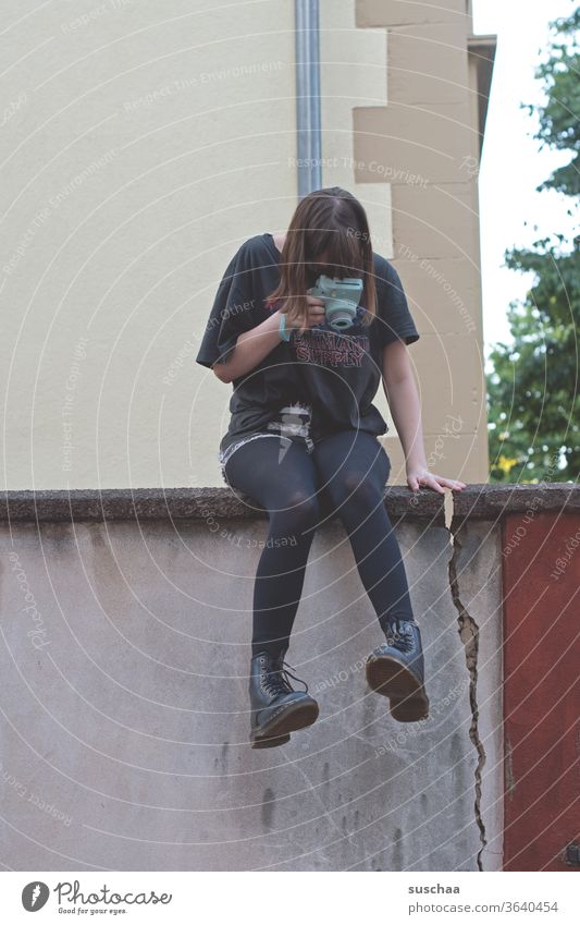 teenagerin, die auf einer mauer sitzt und ihre füße fotografiert Beine Füße Schuhe Stiefel cool sitzen Jugendliche Mauer Mauerriss Außenaufnahme Strumpfhose