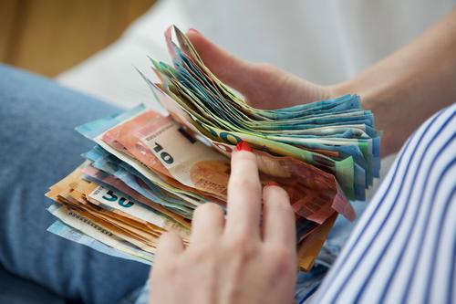 Reisekasse | Junge Frau hält einen Stapel Geldscheine in den Händen und zählt durch. Euro Bargeld zählen sparen Einkommen Reichtum bezahlen kaufen sparsam reich