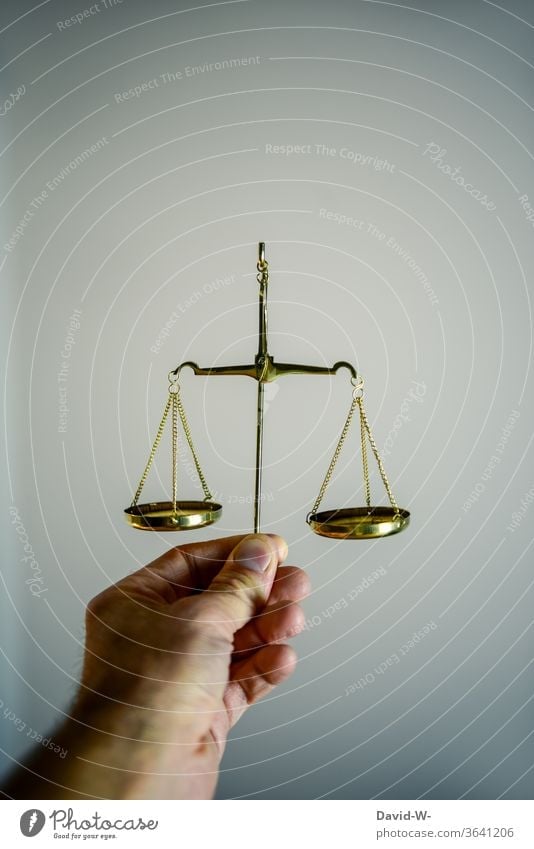 Hand hält eine Waage fest und vergleicht beide Seiten miteiander Zeit Geld Konzept Gleichgewicht Gewicht Gerechtigkeit Ehrlichkeit Justiz u. Gerichte Justitia