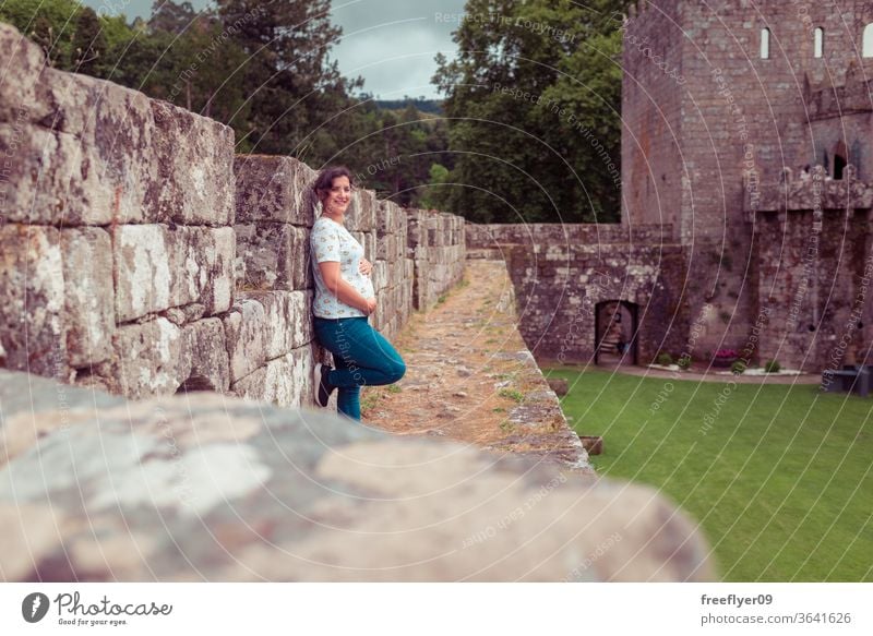 Schwangere Frau auf den Ruinen einer mittelalterlichen Burg schwanger in die Kamera schauen Burg oder Schloss Festungsmauern Zinnen Tourismus reisen Verlassen