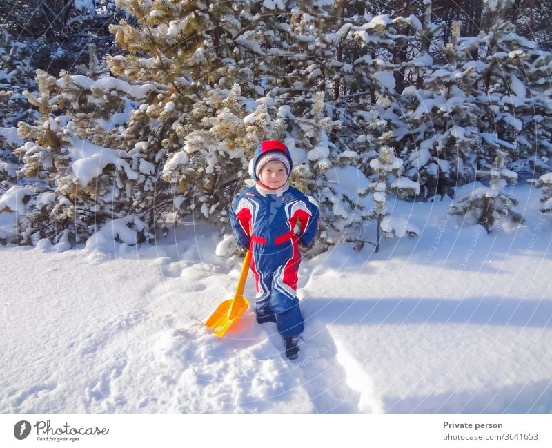 Glücklicher kleiner Junge im Winter in der Nähe eines verschneiten Weihnachtsbaums wenig Weihnachten Kind Spiele im Freien Kindheit Kleidung kalt niedlich