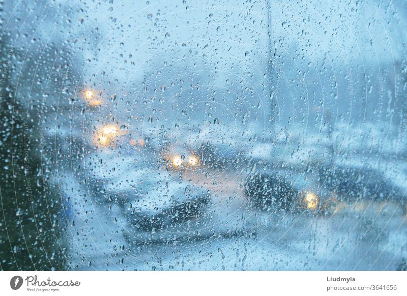 Regentropfen auf einem durchsichtigen Glas. Abends Blick auf den Stadtverkehr. Tröpfchen Autos Marmelade Fahrzeug Verkehr glühend Großstadt Dämmerung Unwetter