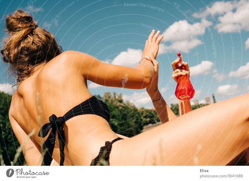 Zwei junge Frauen , die sich amüsieren und sich mit Wasser aus einer Sprühflasche bespritzen baden Sommer Spaß kühlen Mädchen sich[Akk] sonnen Bikini Sonne