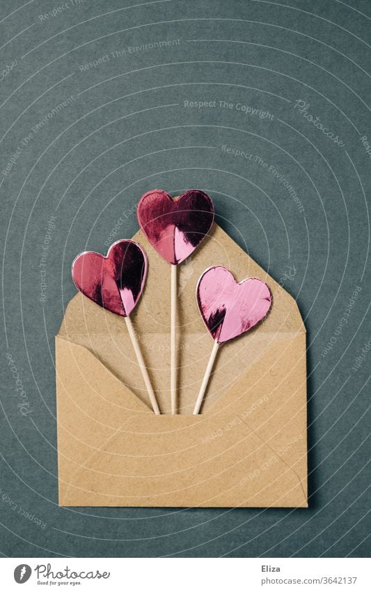 Drei rosa Herzen am Stiel gucken aus einem braunen Briefumschlag raus Liebesgrüße Liebesbrief Kommunizieren Textfreiraum oben Post blau