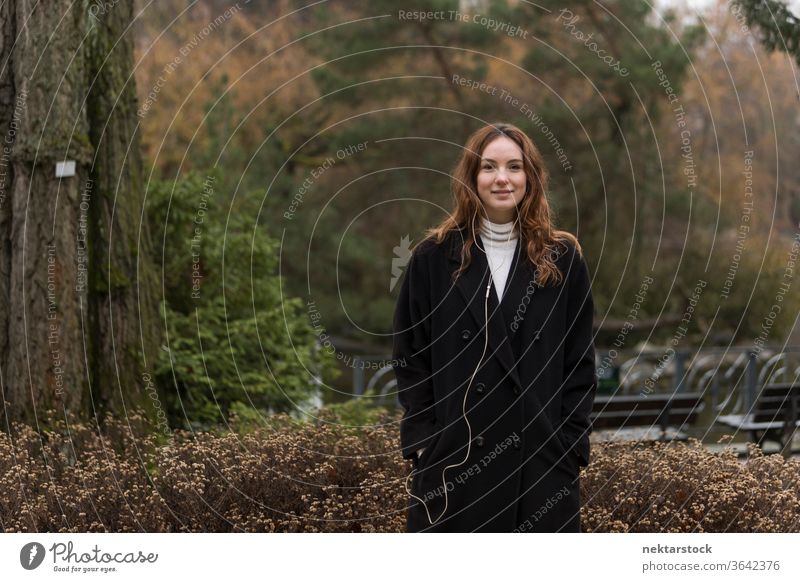Junge kaukasische Frau posiert im Herbstpark kaukasische Ethnizität Kopfhörer Audio Musik hören braune Haare Modell aus dem wirklichen Leben reales Leben