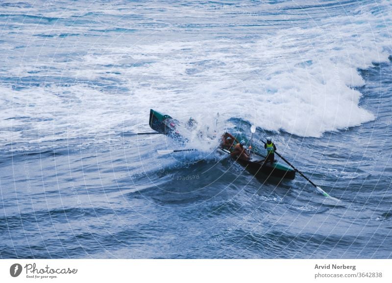 Mutige Männer, die bei einem Ruderwettbewerb direkt in eine brechende Welle stürzen Adrenalin Abenteuer Hintergrund schlecht groß blau Boot Brechen Gemetzel