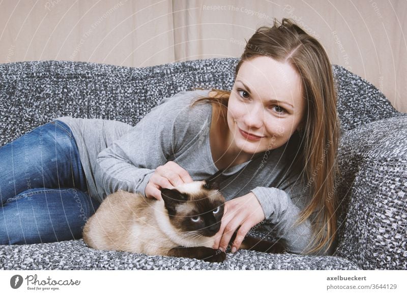 glückliche junge Frau entspannt sich mit Katze auf dem Sofa Haustier Tierliebe Kraulen Streicheln Kuscheln zuhause entspannen Mädchen Zuneigung Erwachsener