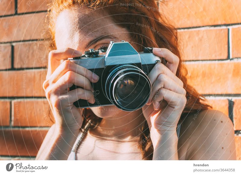 junge Frau hält eine analoge Kamera und schaut durch den Sucher veraltet Antiquität Antike Fotokamera klassisch Klassik klicken abschließen elektronisch Gerät