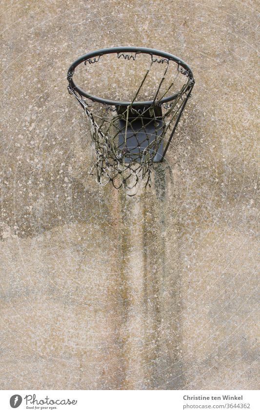 Alter abgenutzter Basketballkorb mit zerfetztem Netz hängt an einer alten verwitterten Betonmauer Basketballnetz kaputt Ballsport Spielen Korb Freizeit & Hobby
