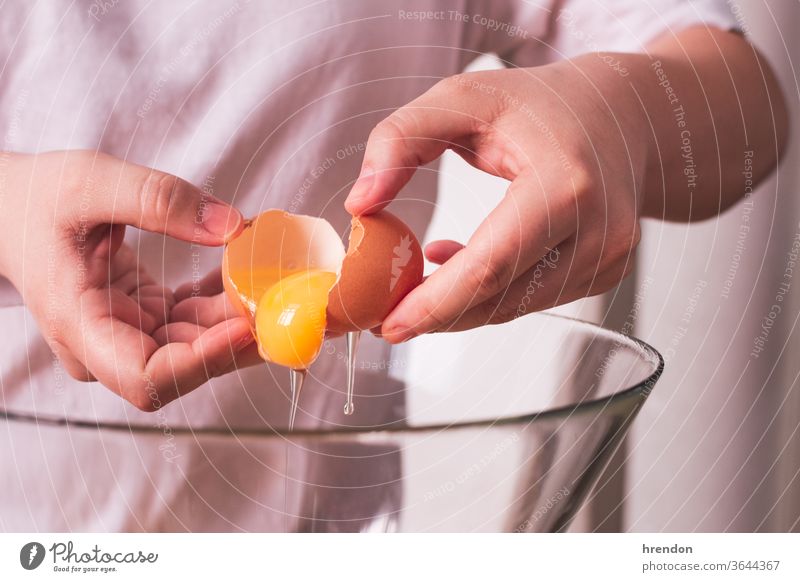 nicht erkennbare Person, die ein Ei in einer Schüssel aufschlägt gebrochen Lebensmittel Panzer backen Pause Essen zubereiten Hand Kochen Utensil hölzern Brechen