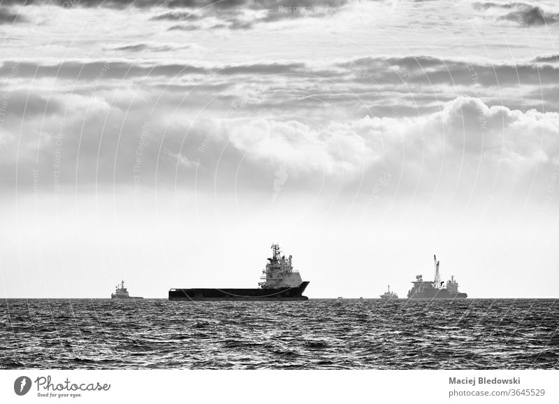 Schwarz-Weiß-Bild von Schiffssilhouetten am Horizont bei Sonnenuntergang. MEER Meer Verkehr reisen Wasser Reise schwarz auf weiß Silhouette Himmel Gefäße Boot