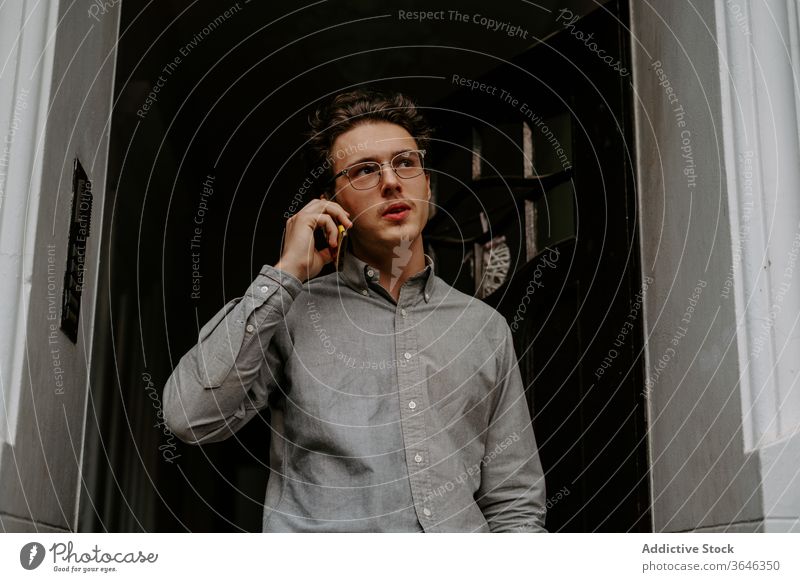 Fokussierter junger Mann spricht auf Smartphone Telefonanruf reden Gespräch Konzentration besinnlich Gang Kommunizieren Gerät Brille Hemd Apparatur Anschluss