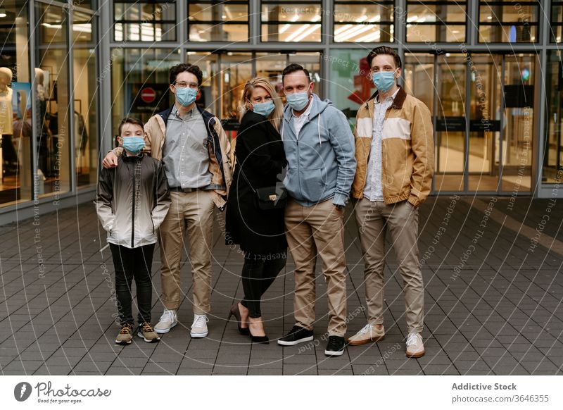 Positive Freunde in Gesichtsmasken gegen Glasgebäude relativ Mundschutz Atemschutzgerät Inhalt positiv Gebäude Tür modern Hand-in-Tasche Stil Coronavirus
