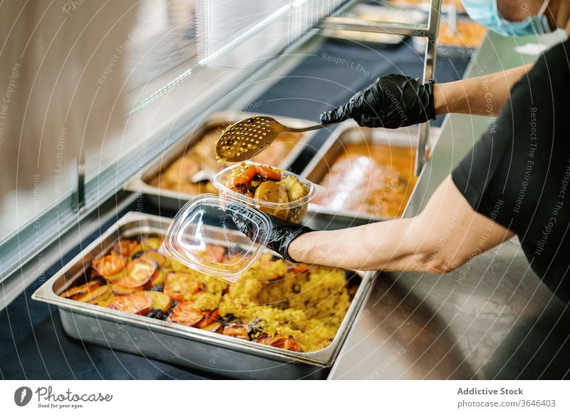 Angestellte in einem Getreidecafé, die Lebensmittel in Plastikbehälter zum Mitnehmen einpacken Kellnerin Atemschutzgerät Rudel Imbissbude Kunststoff Container