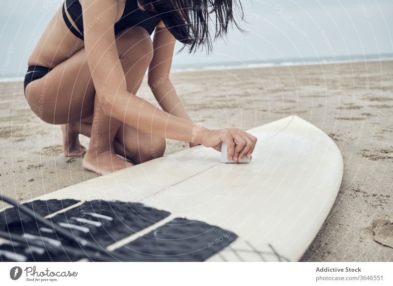 Kropf-Surferin beim Wachsen eines Surfbretts mit Basecoat Frau basecoat vorbereiten Strand sandig sportlich MEER Badebekleidung Aktivität Seeküste sorgenfrei