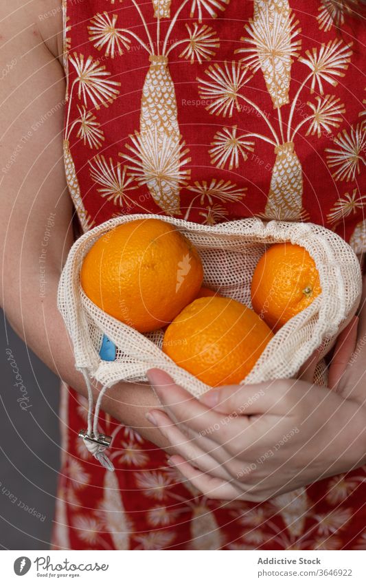Erntehelferin mit frischen Früchten im Schnurbeutel reif orange Einkaufstasche wiederverwenden Frau Tasche umweltfreundlich gesunde Ernährung Frucht Ökologie