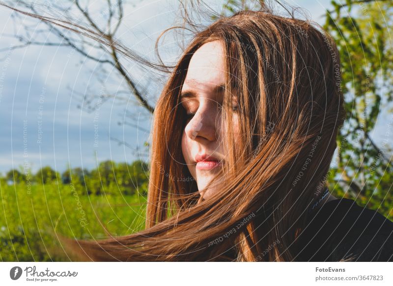 Mädchen steht mit geschlossenen Augen im Sonnenlicht Porträt genießend Natur Mode Tag Schönheit modern attraktiv Baum zugeklappt Stil Behaarung Teenager Person