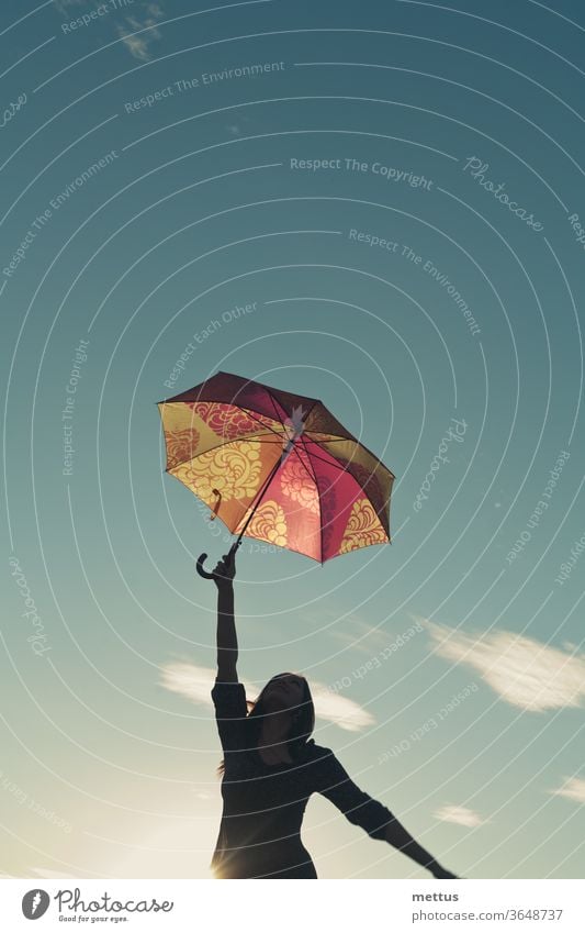 Mädchensilhouette gegen den Himmel streckt sich mit einer Hand, in der sie einen Regenschirm hält, nach oben Frau Freiheit Glück frei Kleid Emotion klassisch